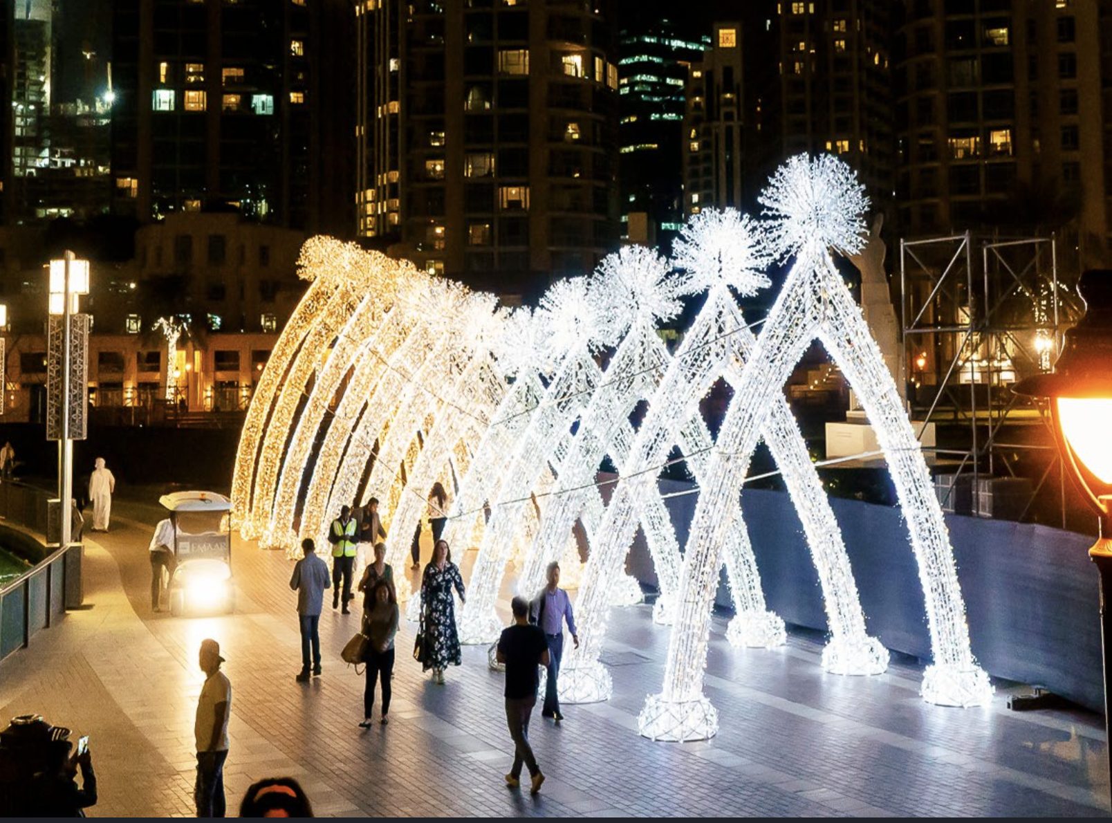 Illuminated arch walkway with pedestrians, Dubai Boulevard at night