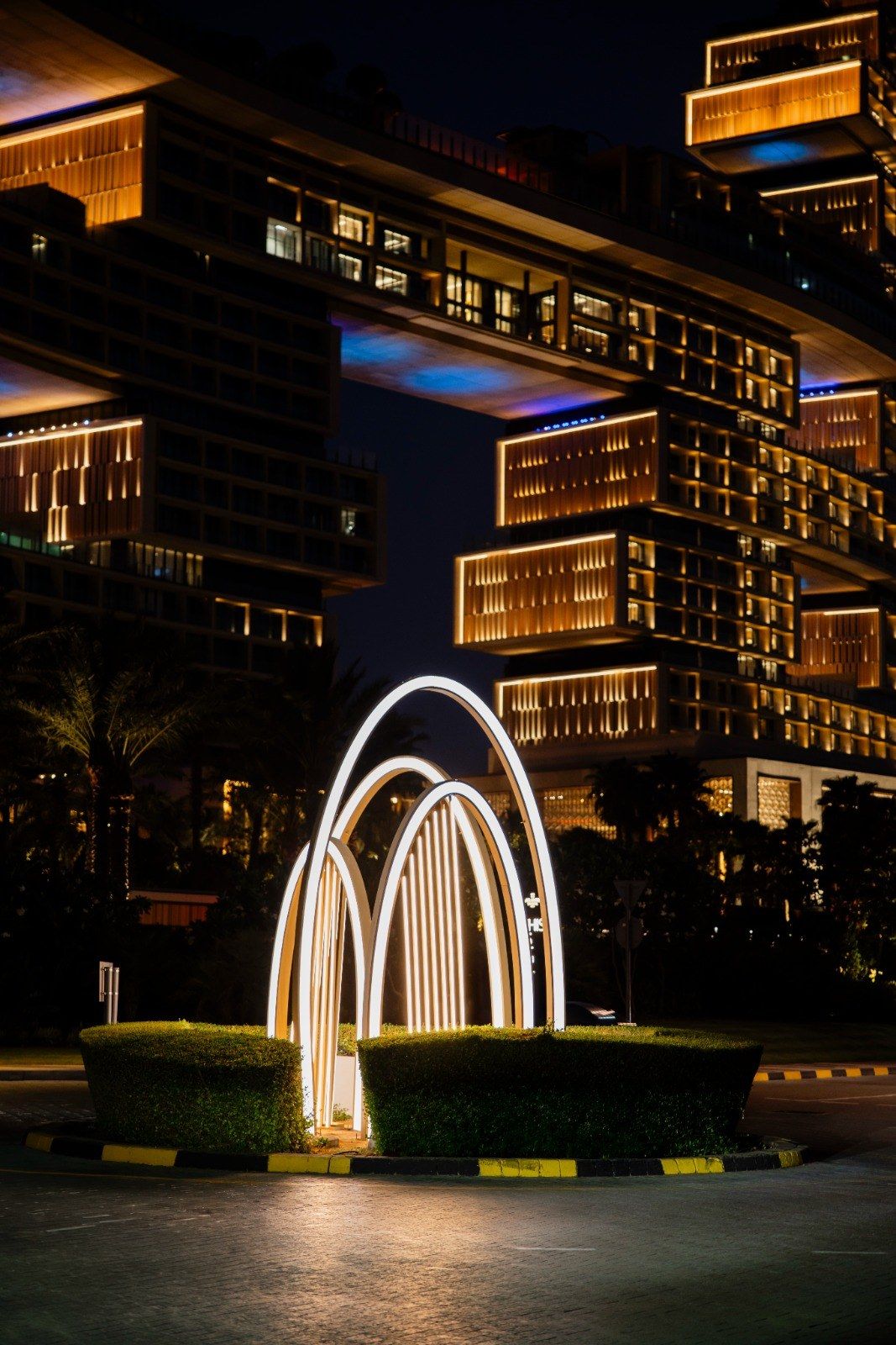 Illuminated light arches installed by Redfox on a landscaped roundabout on The Palm, Dubai, at night